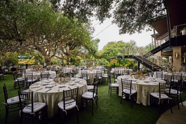 round tables with white linens set on the lawn under oak trees before Cocktails for the Colorado 2026