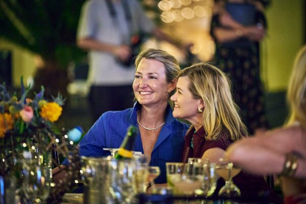 two guests laughing together at a candlelit dinner table