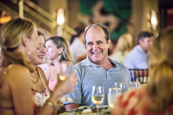 guests laughing and talking over dinner at a crowded table