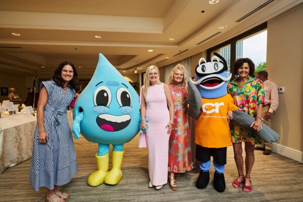 guests posing with a smiling water droplet mascot and a CRA mascot at the cocktail reception